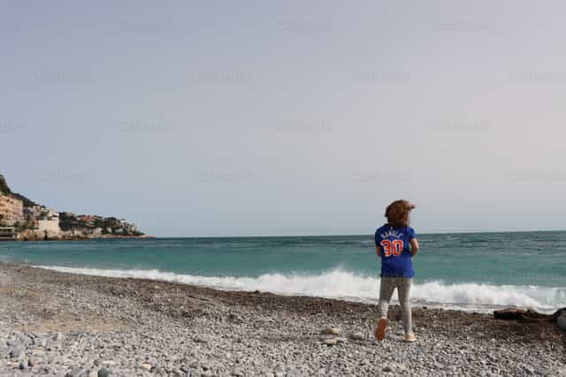 Menina brincando na praia - Imagens católicas de stock