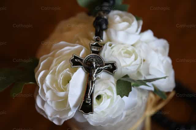 Un crucifix noir posé sur des roses blanches - Images catholiques de stock - Photo de Luisa Oswalt