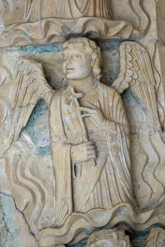 Ángel de piedra tallada sosteniendo una pequeña cruz - Banco de imágenes católicas - Fotografía por Joan Sutter