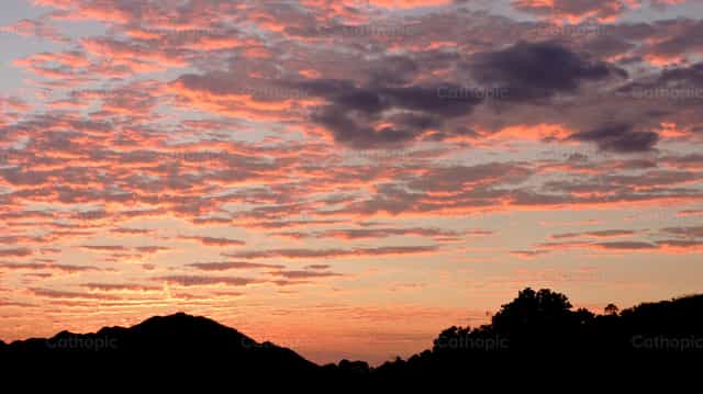 Silhouette of mountains in an orange sunset - Catholic stock images
