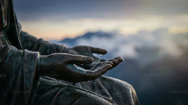 Estátua de mãos abençoadas em gesto de oração com céu de montanha - Imagens católicas de stock
