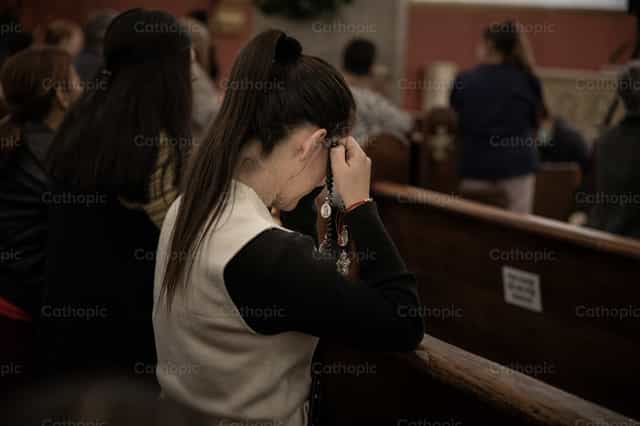 Joven mujer rezando el rosario - Banco de imágenes católicas - Fotografía por Carolina BR