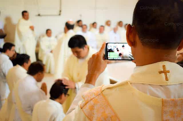 Sacerdote tomando fotografia en misa - Banco de imágenes católicas