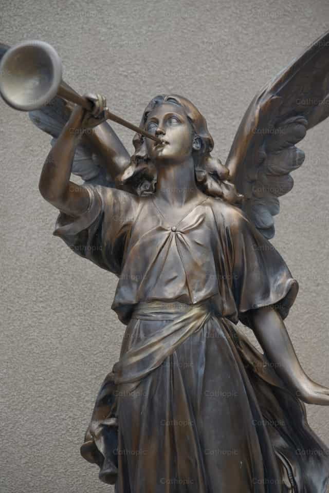 Una estatua de un ángel que sopla un cuerno - Banco de imágenes católicas - Fotografía por Luisa Oswalt