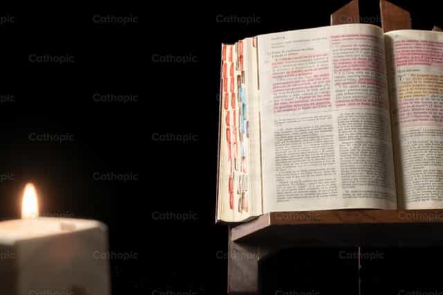 Bible on a wooden base by candlelight - Catholic stock images - Photo by Piero Insfran