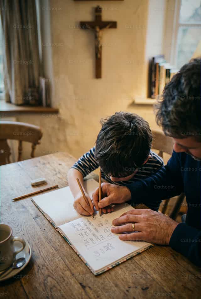 Hand van een volwassene die een kind begeleidt bij het schrijven op papier - Katholieke stockfoto's - Foto door Enma Bastidas