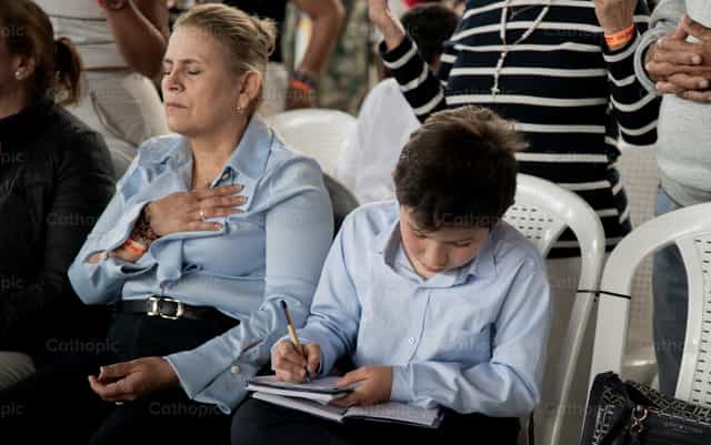 Una donna in preghiera accanto a un’adolescente - Immagini stock cattoliche - Foto di Carolina BR