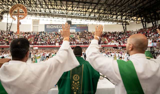 Sacerdotes com as mãos erguidas diante da congregação - Imagens católicas de stock - Foto de Carolina BR