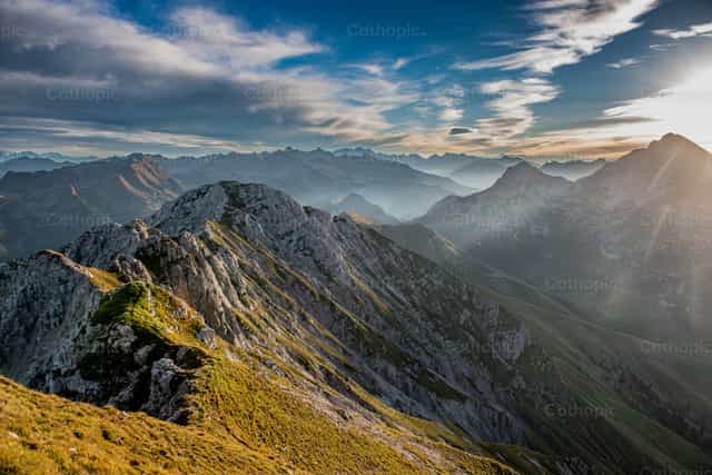 Picos de montaña al atardecer con un cielo ardiente - Banco de imágenes católicas