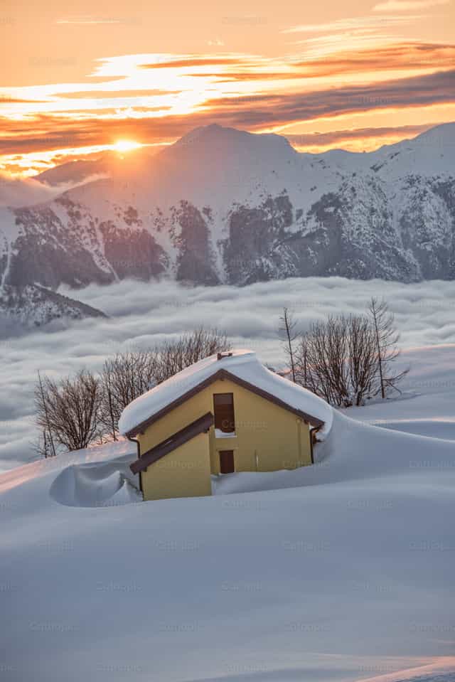 Geel huis bijna bedolven onder diepe sneeuw op de berg - Katholieke stockfoto's