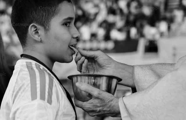 Un niño recibe la Eucaristía - Banco de imágenes católicas