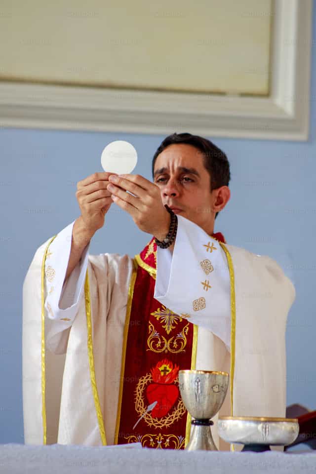 Un prêtre consacrant la Sainte Hostie - Images catholiques de stock