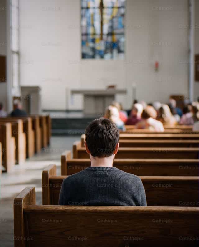 Young man praying in a church - Catholic stock images - Photo by Noemí Márquez