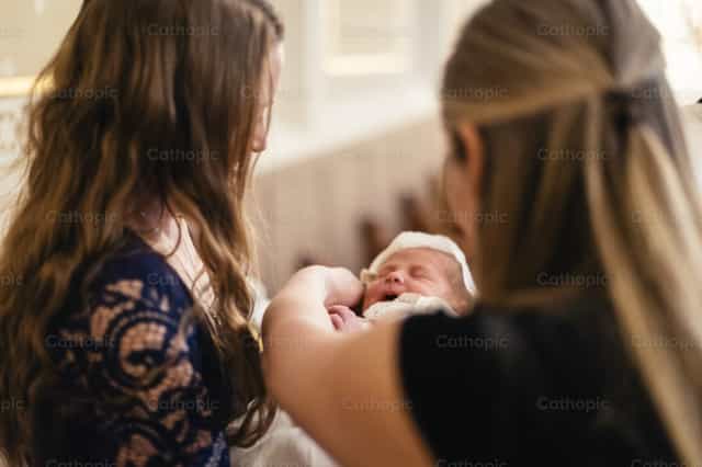 Inaalalayan ng ina ang sanggol sa binyag - Mga Catholic stock image