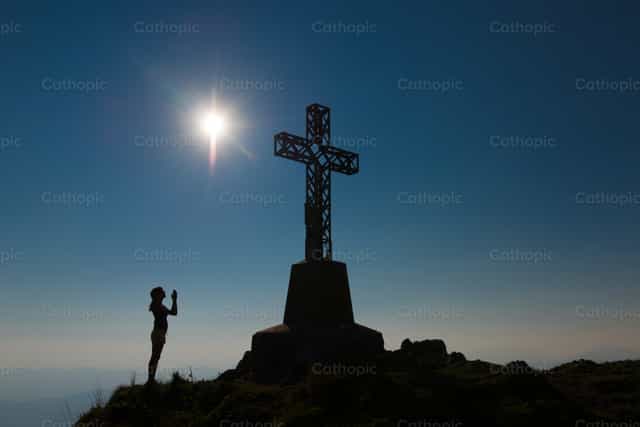 Nanalangin ang babae sa harap ng bundok patungo sa tuktok - Mga Catholic stock image