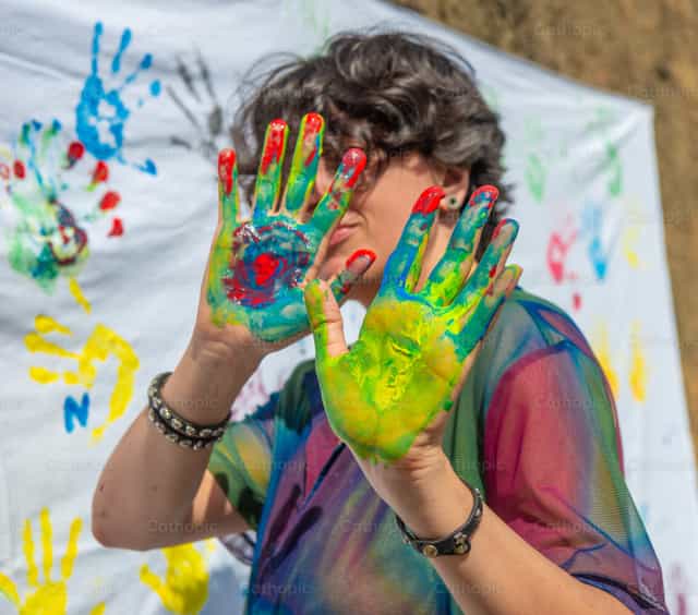Hands with colorful paint leaving prints on a white cloth during an art event - Catholic stock images - Photo by Pierluigi Palazzi