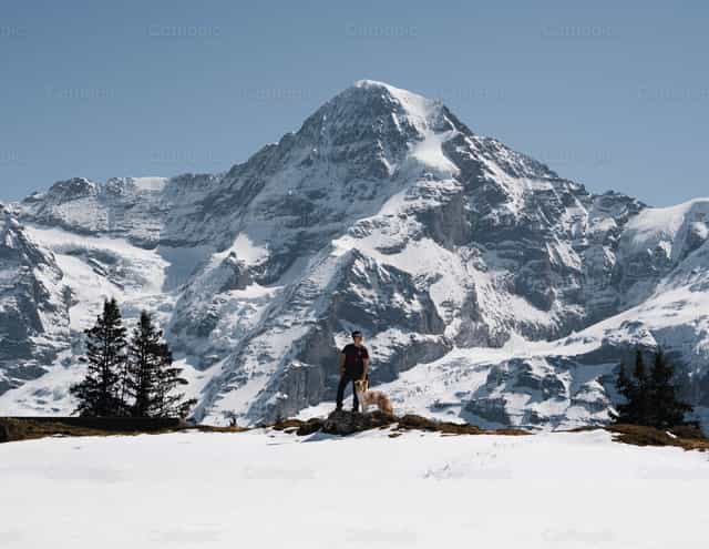 Joven con su mascota en las montañas nevadas - Banco de imágenes católicas