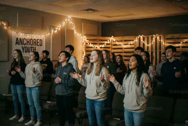 Mga kabataang kumakanta sa youth group na may karatulang ANCHORED - Mga Catholic stock image - Larawan ni Noemí Márquez
