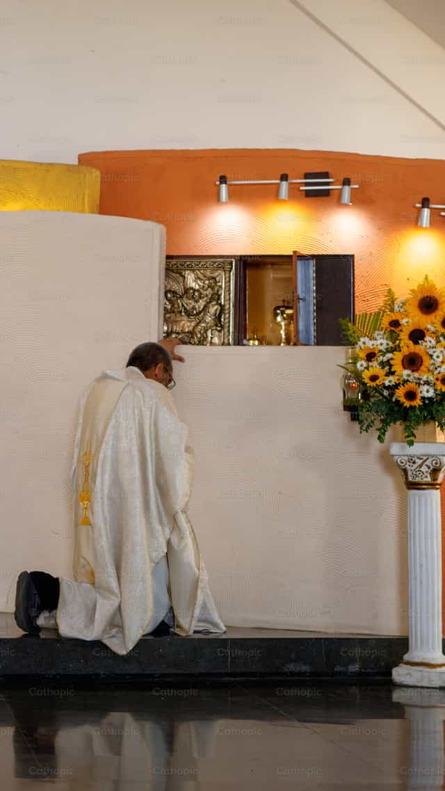 Un prêtre faisant une génuflexion devant le tabernacle - Images catholiques de stock