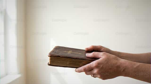 Mga kamay ng adulto na may hawak na Bibliyang may balat na pabalat - Mga Catholic stock image - Larawan ni Enma Bastidas