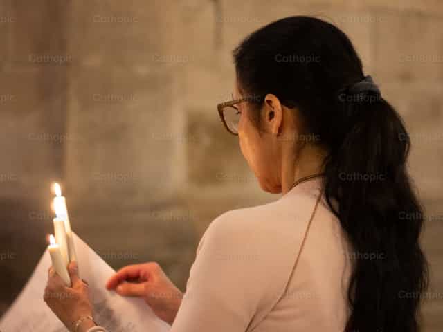 Femme priant avec des cierges - Images catholiques de stock