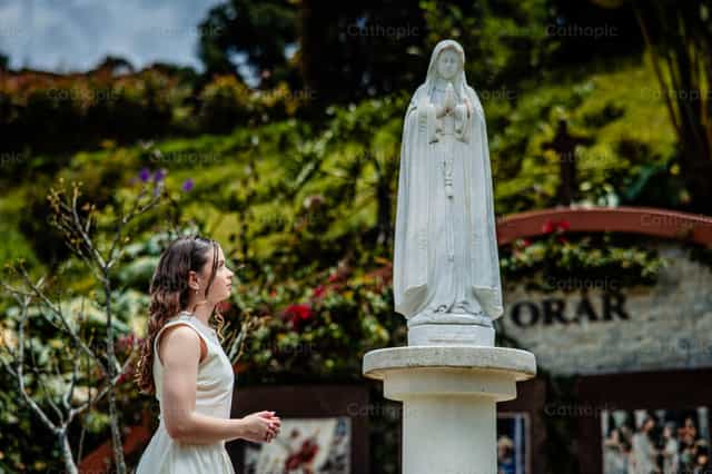 Una persona joven rezando ante Nuestra Señora de Fátima - Banco de imágenes católicas