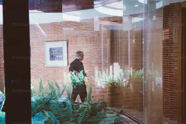 Sacerdote caminando hacia la oficina parroquial - Banco de imágenes católicas - Fotografía por Almures Studio