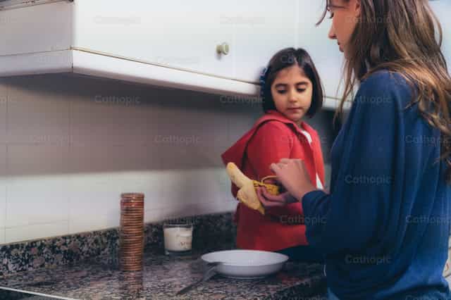 Mãe e filha preparando o café da manhã - Imagens católicas de stock