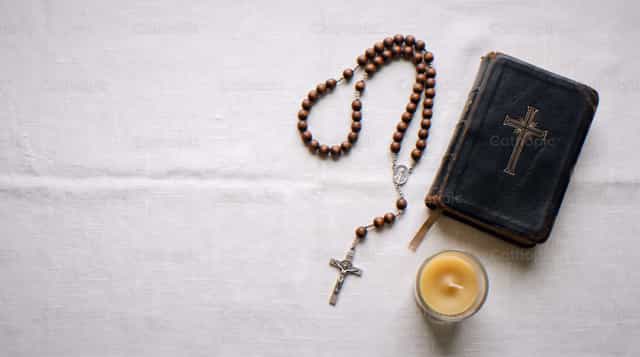 Bruine rozenkrans, zilveren crucifix, zwarte Bijbel, brandende kaars - Katholieke stockfoto's - Foto door Enma Bastidas
