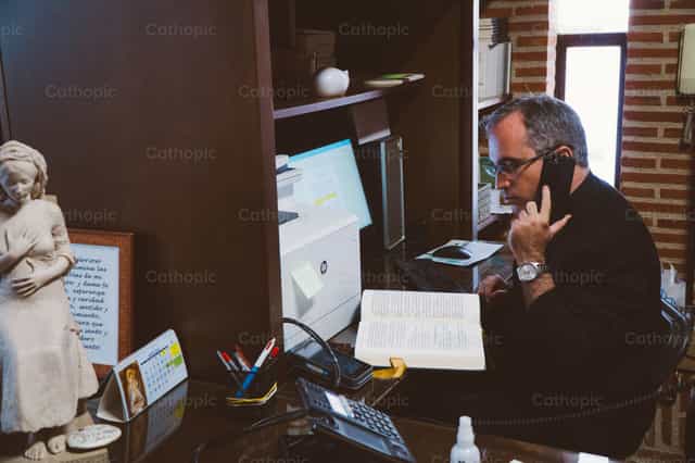 Sacerdote llamando por telefono - Banco de imágenes católicas