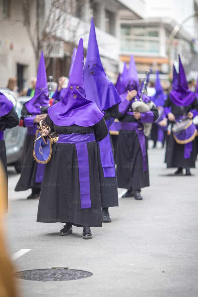 Cofrade con capirote tocando en procesión España - Banco de imágenes católicas - Fotografía por Yandry Fernández Perdomo