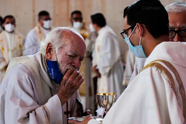 Sacerdote recebendo a Comunhão - Imagens católicas de stock