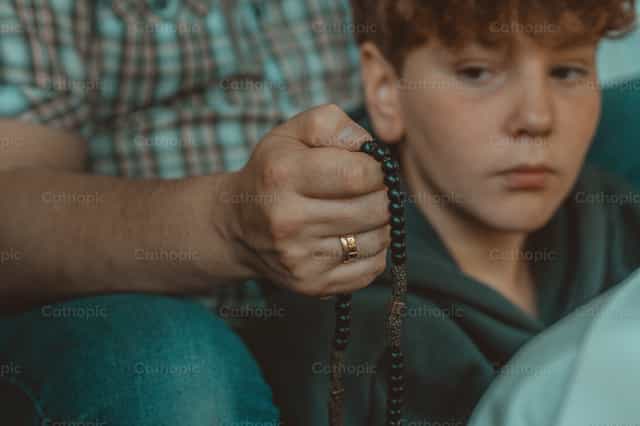 Un padre rezando el rosario con su hijo - Banco de imágenes católicas - Fotografía por Rodrigo De Miguel