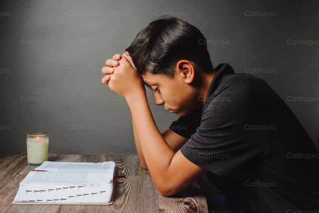 Joven orando con la Biblia - Banco de imágenes católicas