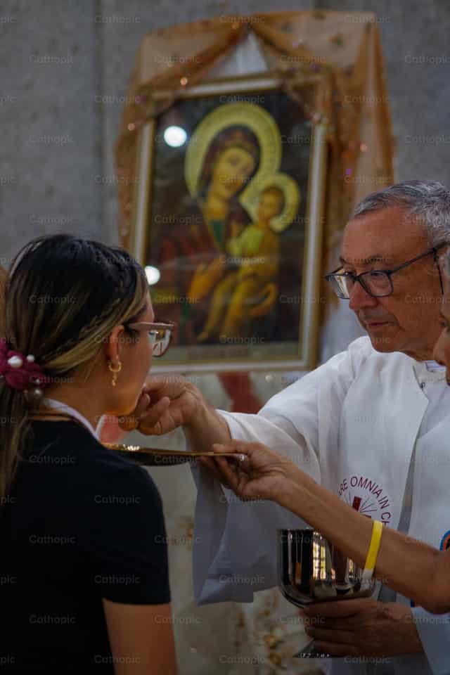 Sacerdote dando la comunión y al fondo la Virgen - Banco de imágenes católicas - Fotografía por Andrés José Barbera Zambrano