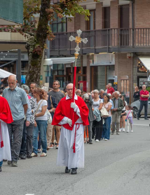 Procesión religiosa encabezada por el portador de la cruz por las calles - Banco de imágenes católicas - Fotografía por Pierluigi Palazzi