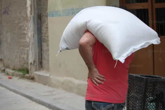 Man carrying a heavy load on his back - Catholic stock images - Photo by Yandry Fernández Perdomo