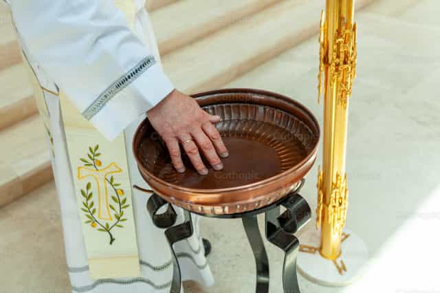 O sacerdote abençoa a água de uma pia batismal - Imagens católicas de stock - Foto de Antonio Gravante