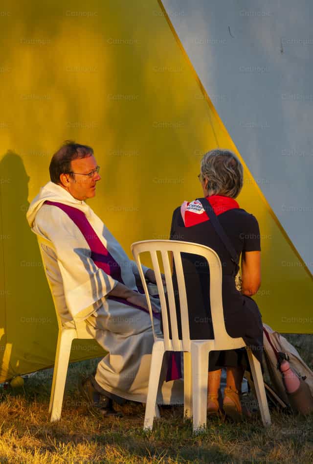 Sacerdote católico escuchando confesión al aire libre - Banco de imágenes católicas - Fotografía por Joan Sutter