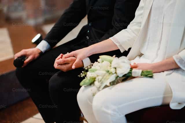 Novios tomados de la mano en ceremonia de matrimonio - Banco de imágenes católicas
