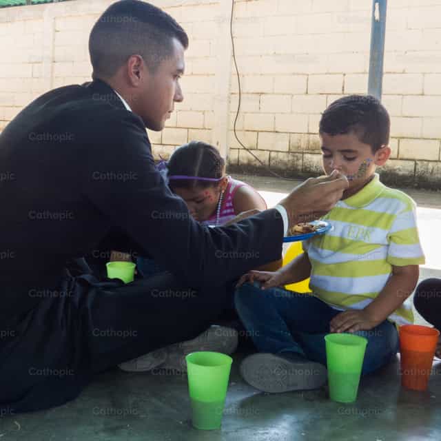 Sacerdote alimentando un nino - Banco de imágenes católicas - Fotografía por Carlos Daniel