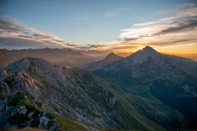 Picos de montaña al atardecer con un cielo ardiente - Banco de imágenes católicas