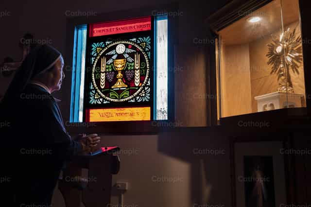 Sœur en prière devant le Saint-Sacrement - Images catholiques de stock