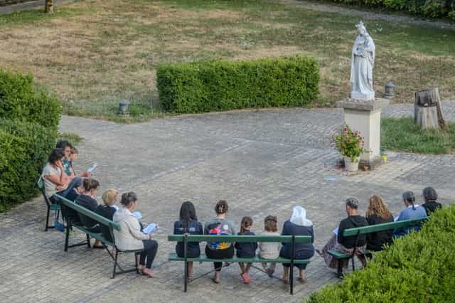 Pilgrims praying near a Virgin Mary statue - Catholic stock images - Photo by Joan Sutter