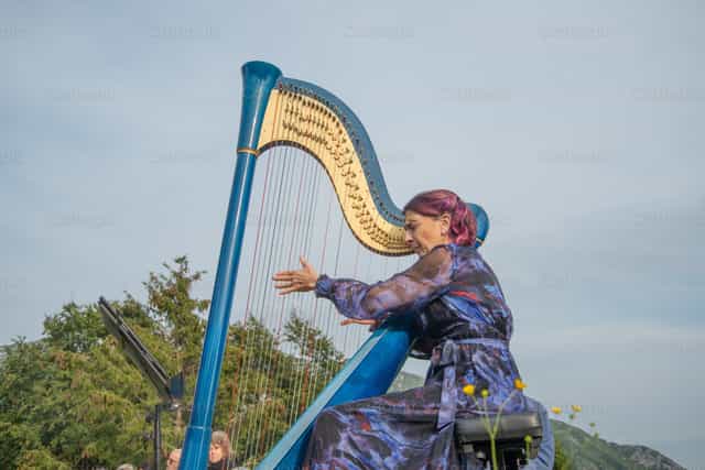 Una arpista suona un’arpa blu durante un concerto all’aperto - Immagini stock cattoliche - Foto di Pierluigi Palazzi