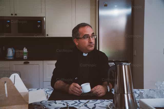 Padre na cozinha esperando a refeição do dia - Imagens católicas de stock