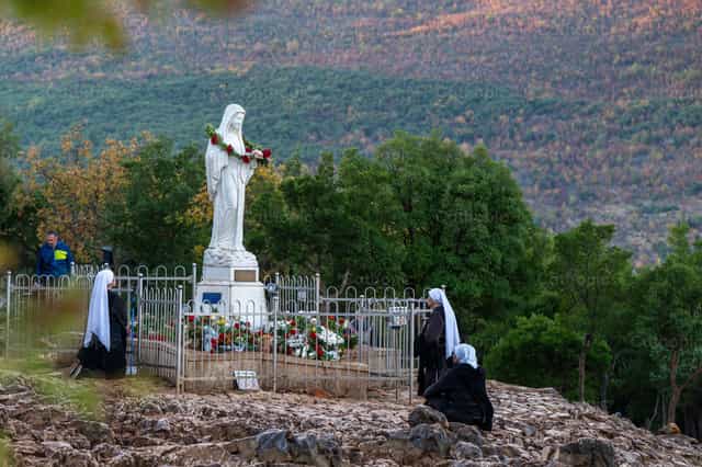 Nuns pray beside the statue of the Queen of Peace - Catholic stock images - Photo by Metod Perme