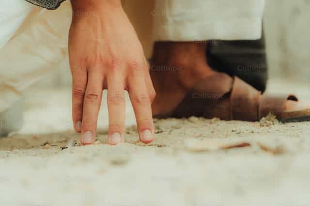 Jesús escribe en la arena - Banco de imágenes católicas - Fotografía por Almures Studio
