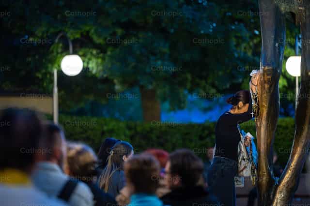 Una mujer reza junto a la estatua del Resucitado - Banco de imágenes católicas - Fotografía por Metod Perme