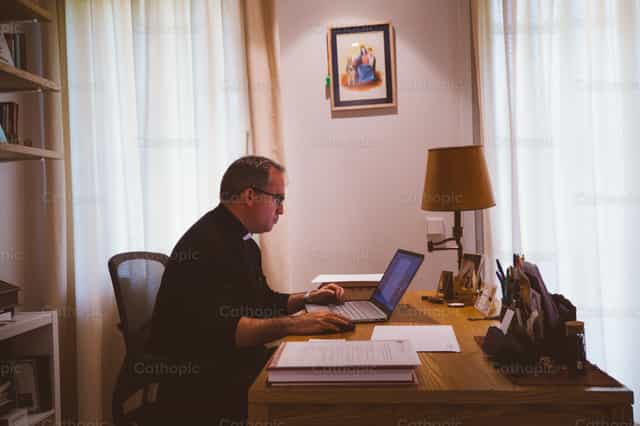 Sacerdote trabajando en su oficina - Banco de imágenes católicas